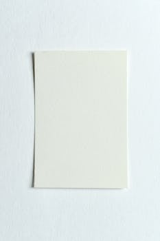 Top view of a white paper sheet on a textured white background, perfect for designs.