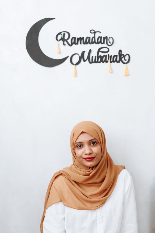 Free Portrait of a woman in hijab with 'Ramadan Mubarak' sign, symbolizing festive spirit. Stock Photo