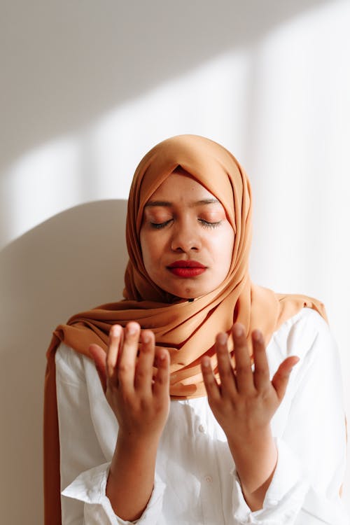 Photo of a Woman in a Brown Hijab Praying