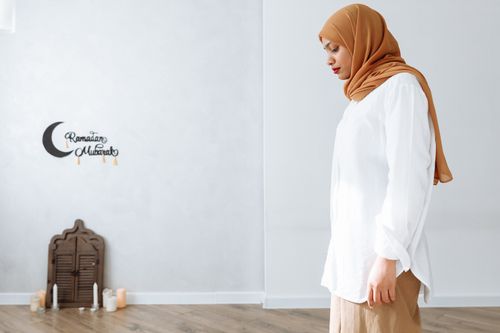 Free A woman wearing a hijab stands indoors with Ramadan decorations nearby, expressing cultural and religious sentiment. Stock Photo