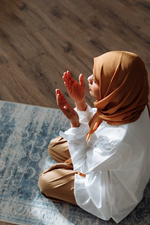 Woman in Brown Hijab praying with her Arms Open 