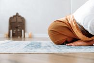 Woman in Brown Hijab kneeling on a Prayer Rug