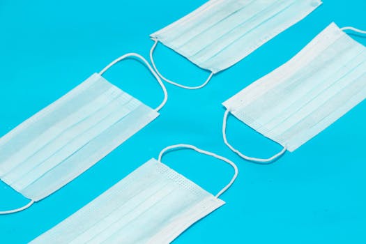 Top view of disposable medical face masks on a blue background, ideal for health and hygiene themes.