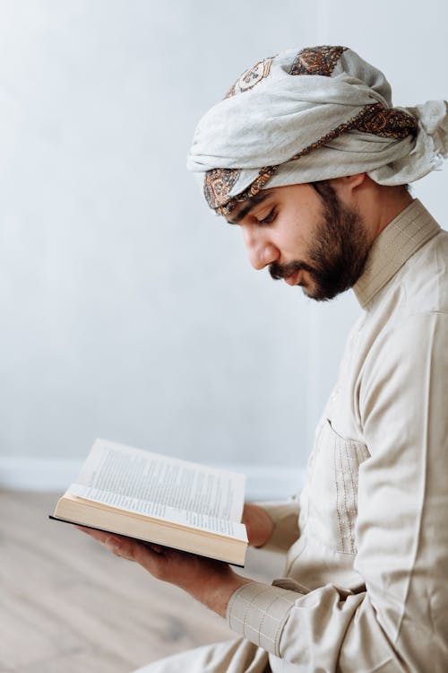Free Man in Traditional Wear reading Koran  Stock Photo