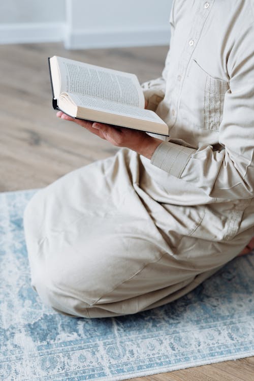 Free Person in Beige Clothing reading Koran  Stock Photo