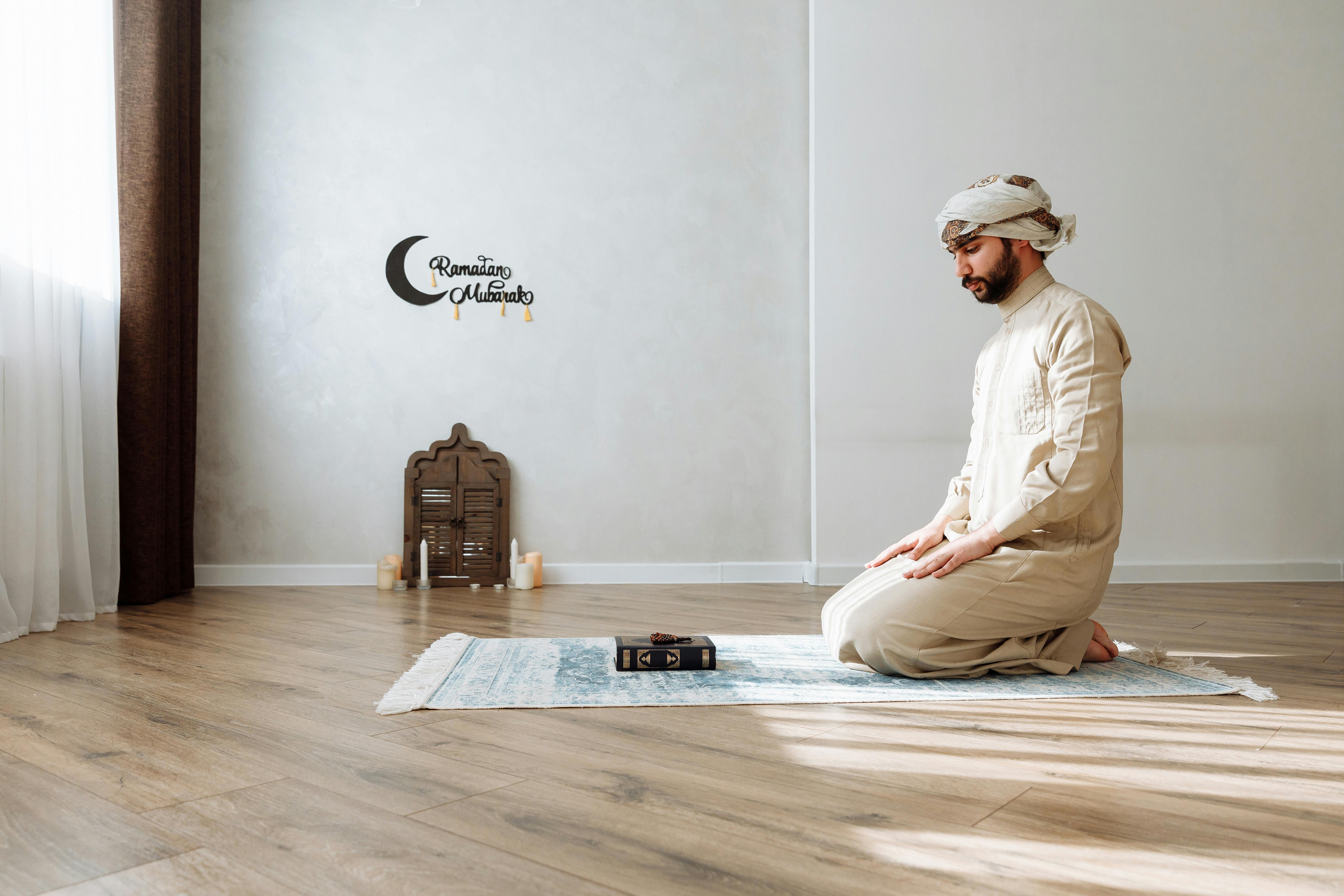 man in traditional wear kneeling on a prayer rug