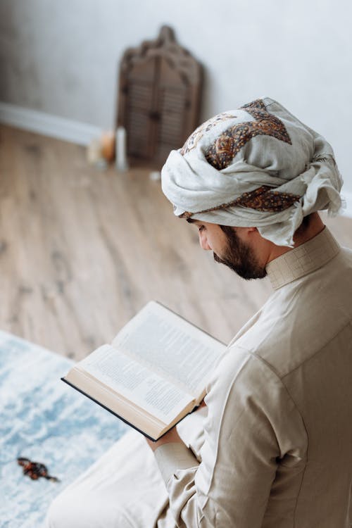 Free Man in Traditional Wear reading Koran Stock Photo