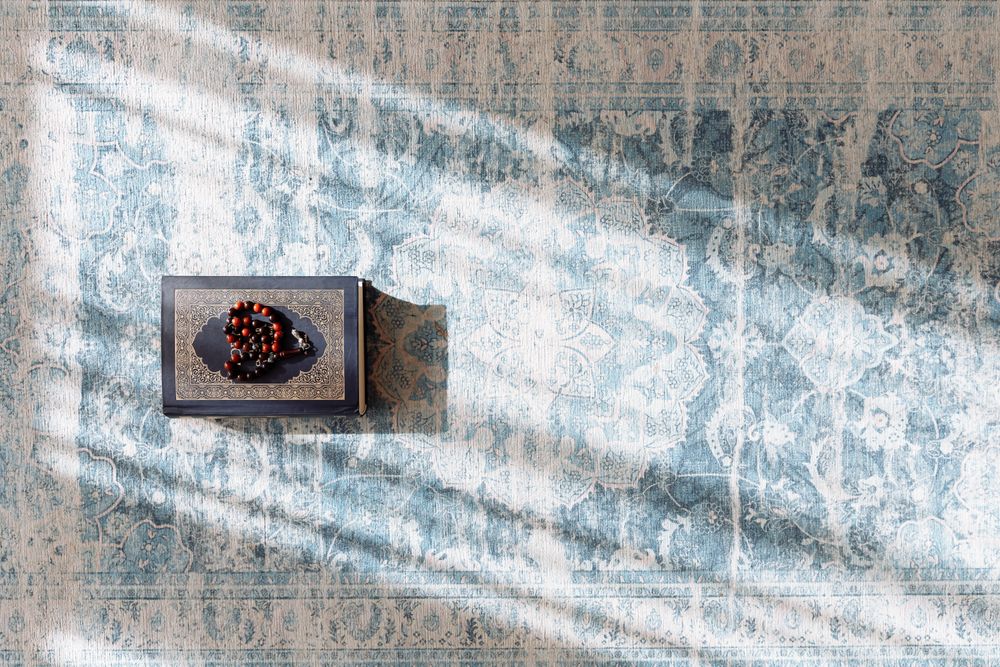 Quran and prayer beads arranged on a prayer rug
