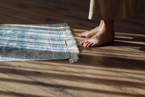 Free A pair of bare feet stands on a prayer rug in a sunlit room, capturing a serene and spiritual moment. Stock Photo