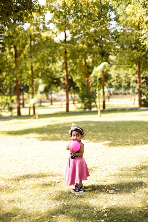 Free Girl in Pink Dress Standing on Green Grass Field Stock Photo
