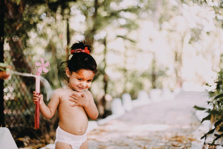 A Shirtless Girl Holding Toy Fan