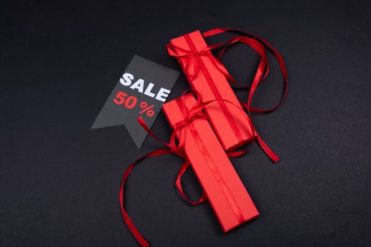 Red gift boxes with ribbons and a 50% sale tag on a dark background. - Fotografer Sidoarjo