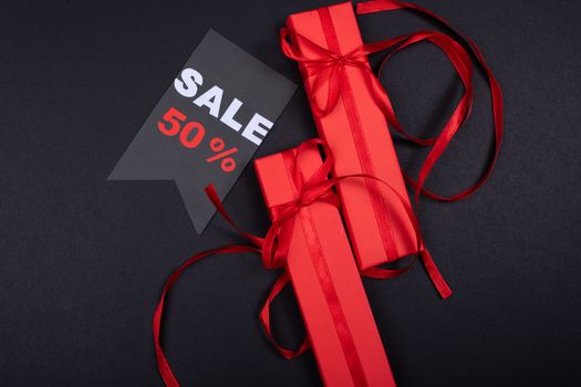 Red gift boxes with ribbons and a prominent 50% sale sign on black background. - Fotografer Sidoarjo