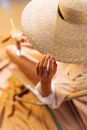 Person Touching The Brim of a Straw Hat