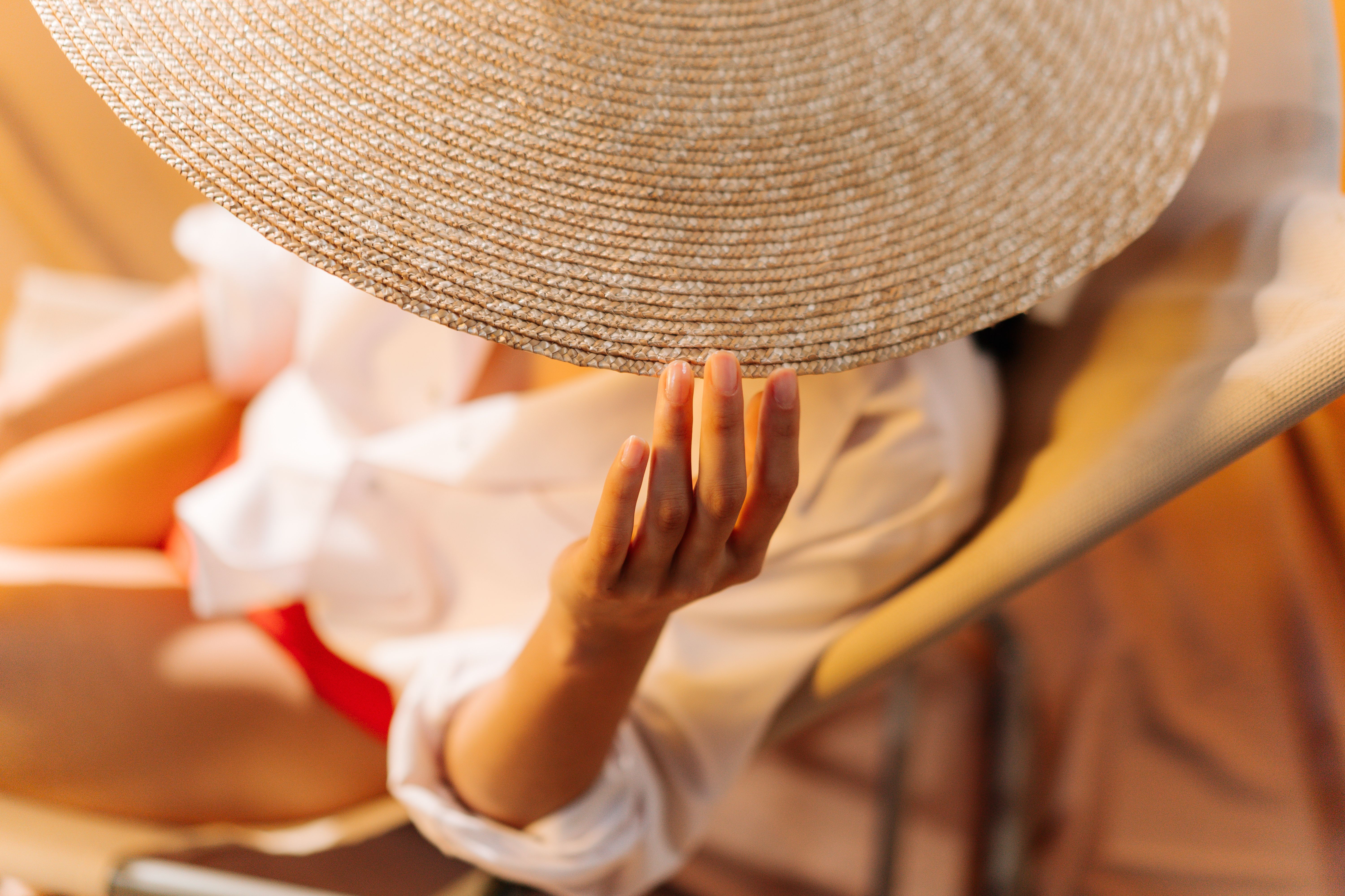 A close-up of a person in a straw hat relaxing outdoors, showcasing summer vibes.