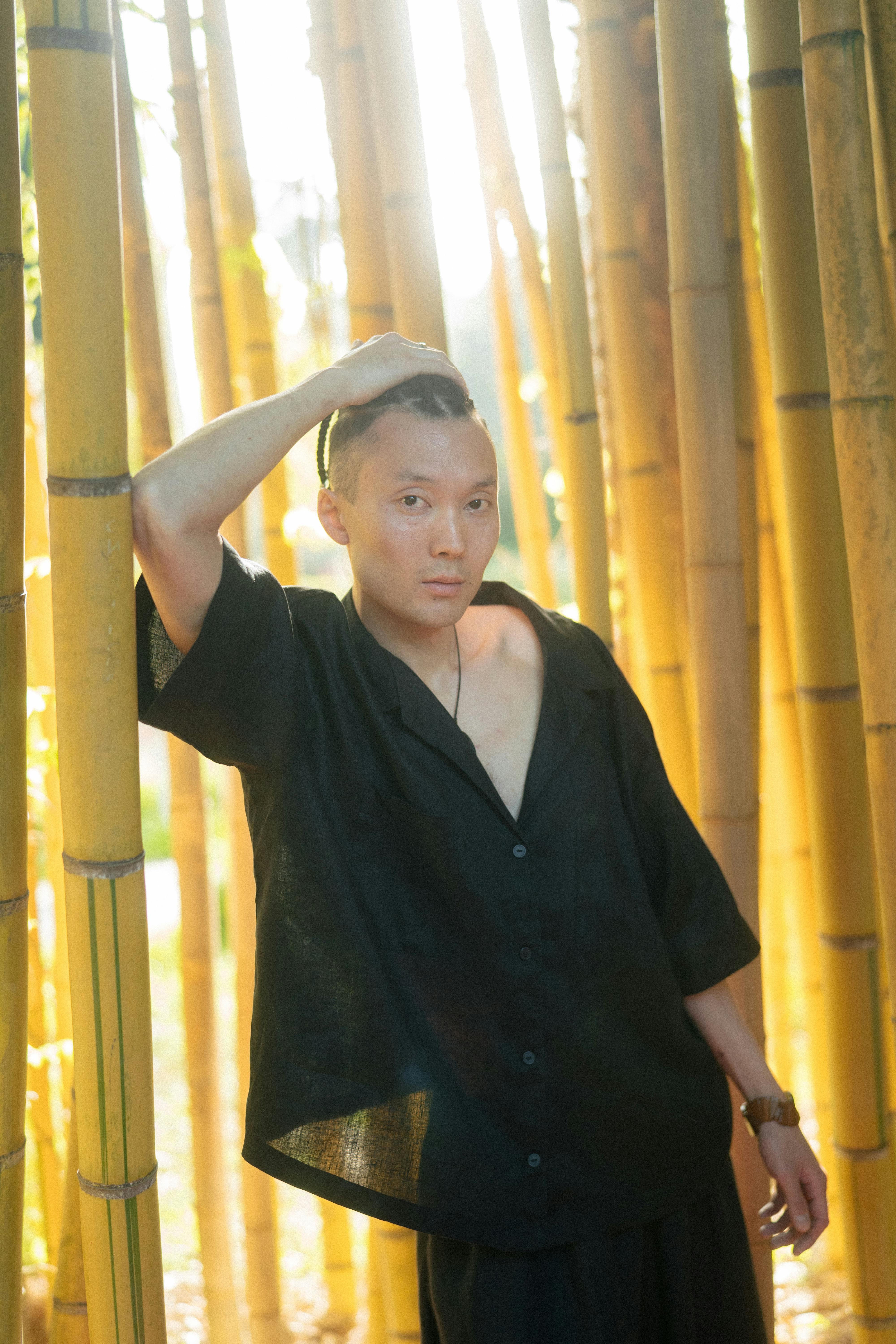 man in black button up shirt standing near bamboo stalks