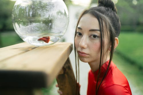 Free Woman in Red Shirt Looking At A Fish Bowl Stock Photo