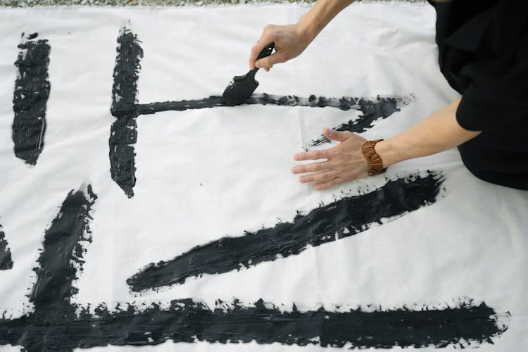 Person Doing Japanese Calligraphy On White Textile