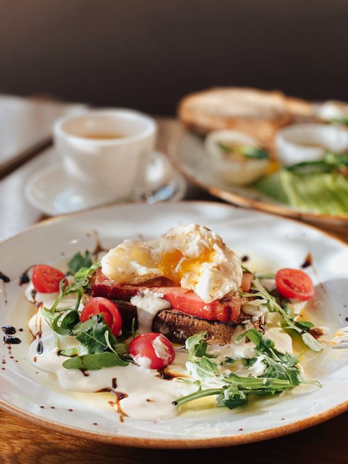 Free Delicious breakfast dish featuring a poached egg, arugula, and cherry tomatoes. Stock Photo