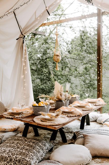 Elegant boho dining setup in outdoor garden with cozy pillows and table decor.