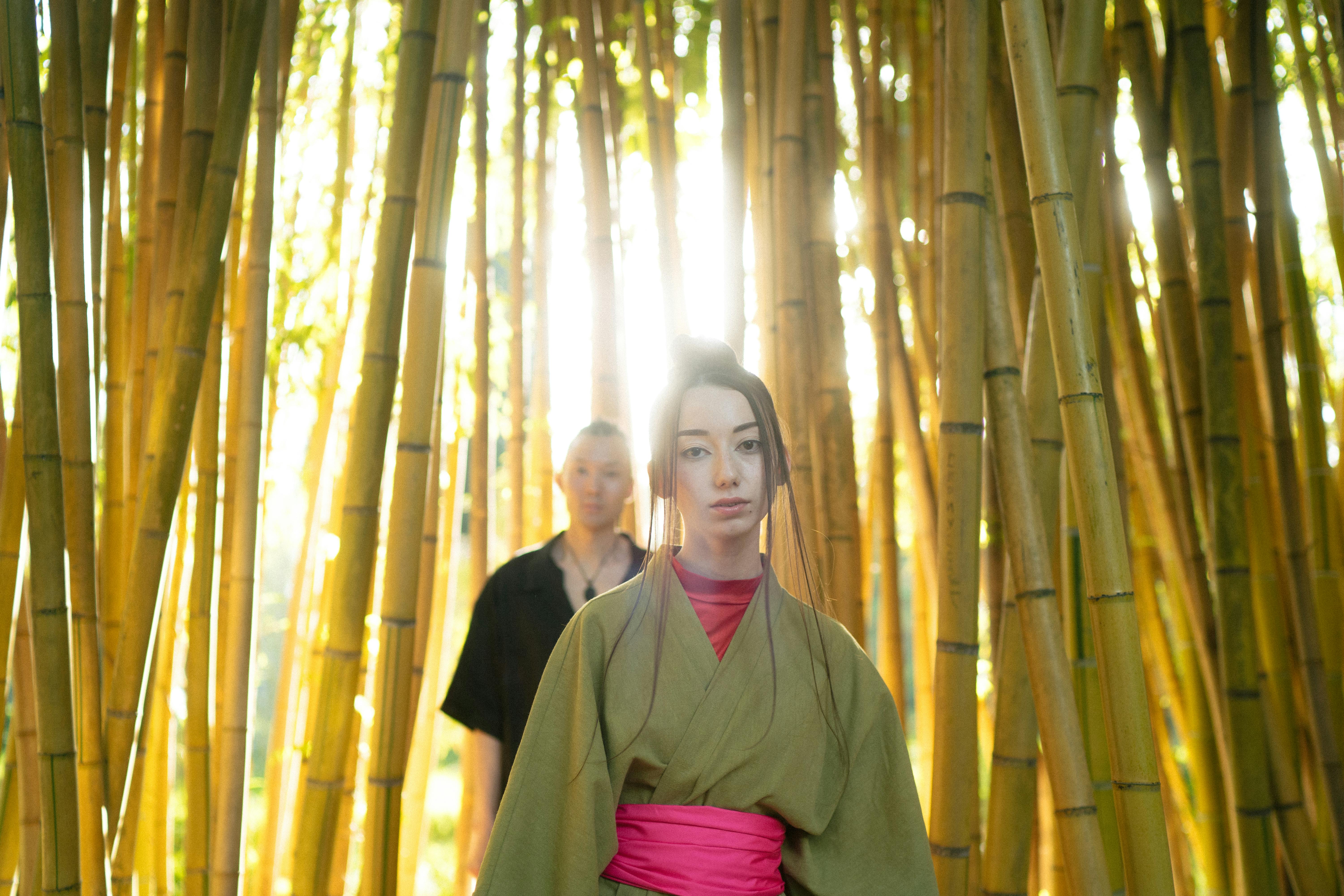 man and woman in their traditional clothes standing near bamboo trees