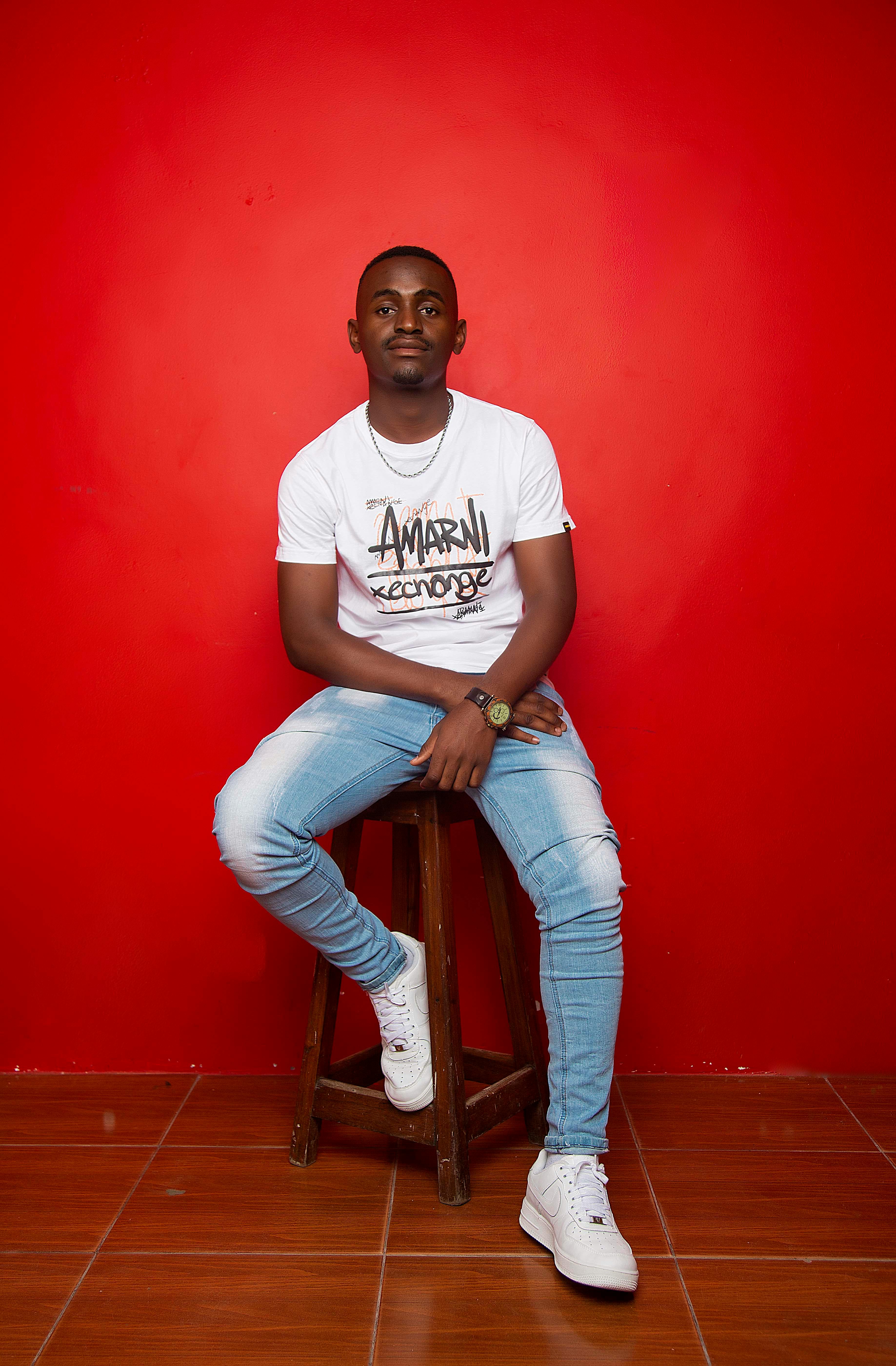 Confident man in casual attire sitting on a stool, showcasing modern style.