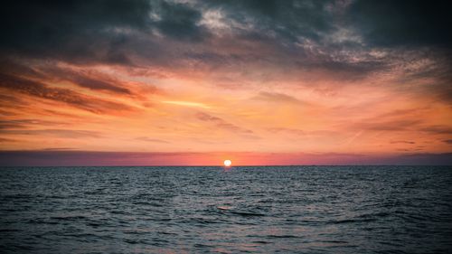 Free A breathtaking view of the ocean at sunset with a vibrant sky and calm waters. Stock Photo