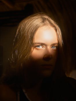 Dramatic portrait of a woman with blue eyes in a play of light and shadow.