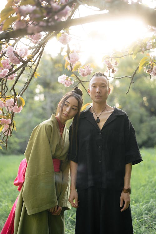 Man And Woman In Their Traditional Outfit Standing Under A Cherry Blossom Tree