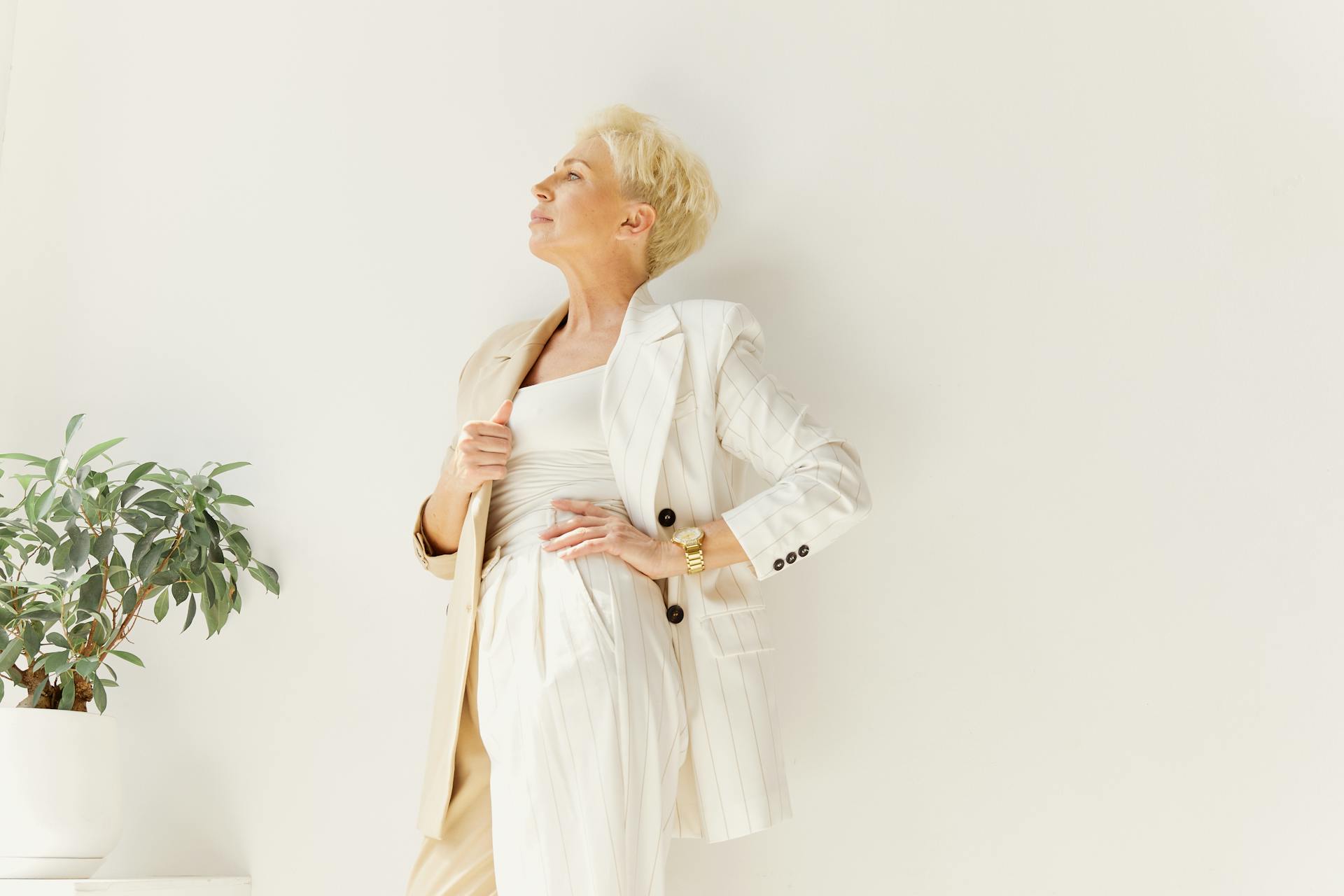 Woman in White Business Attire Standing Near a Plant