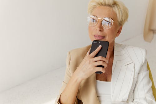 Photo of a Woman with Eyeglasses Holding Her Black Mobile Phone