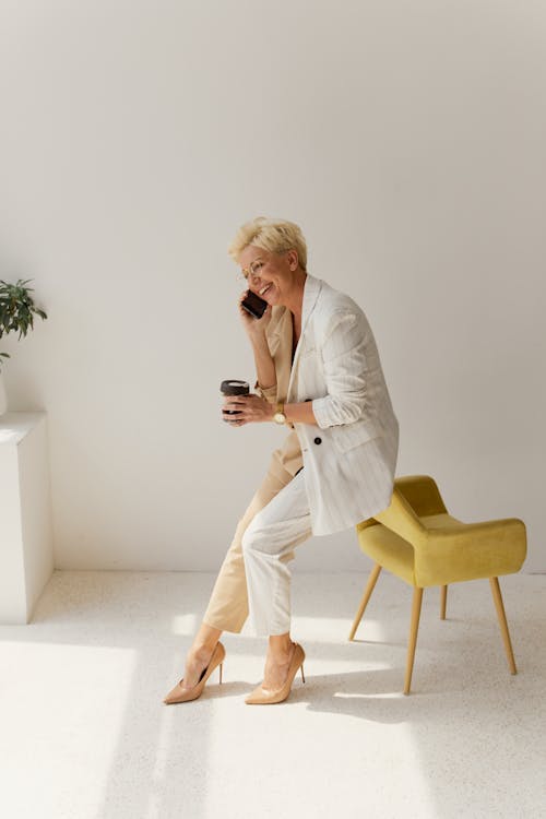 Free A Businesswoman Talking on the Phone while Sitting on a Chair Stock Photo