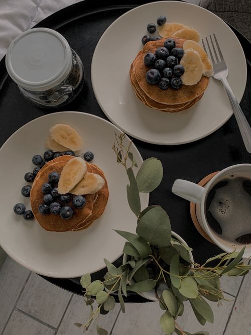 Free Two plates of pancakes with bananas and blueberries, served with coffee on a black tray. Stock Photo