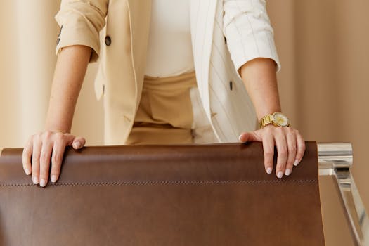 Close-up of a businesswoman's hands on a leather chair, showcasing style and professionalism.