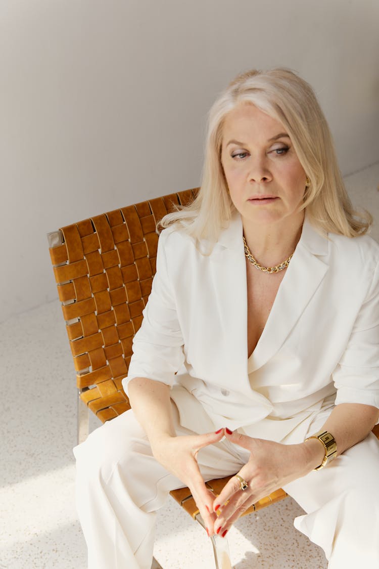 A Woman In White Blazer Sitting On Brown Chair