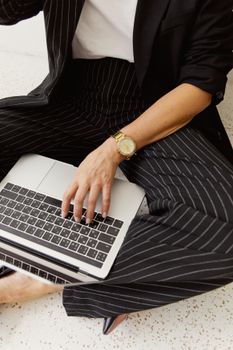 Close-up of a woman in pinstripe attire typing on a laptop, creating a professional work environment.