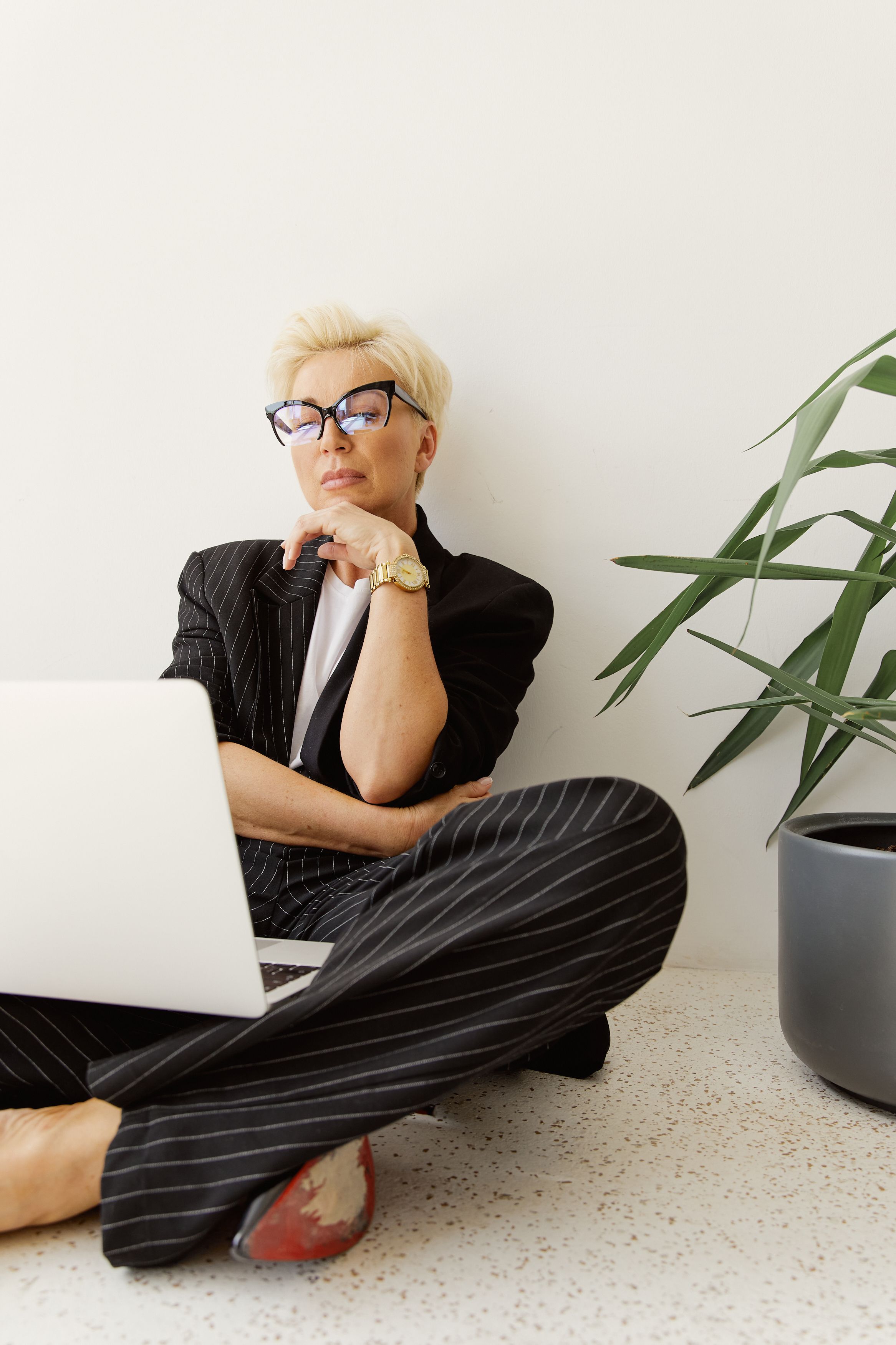 Woman in Formal Attire Sitting on the Floor while Looking at the Screen of a Laptop