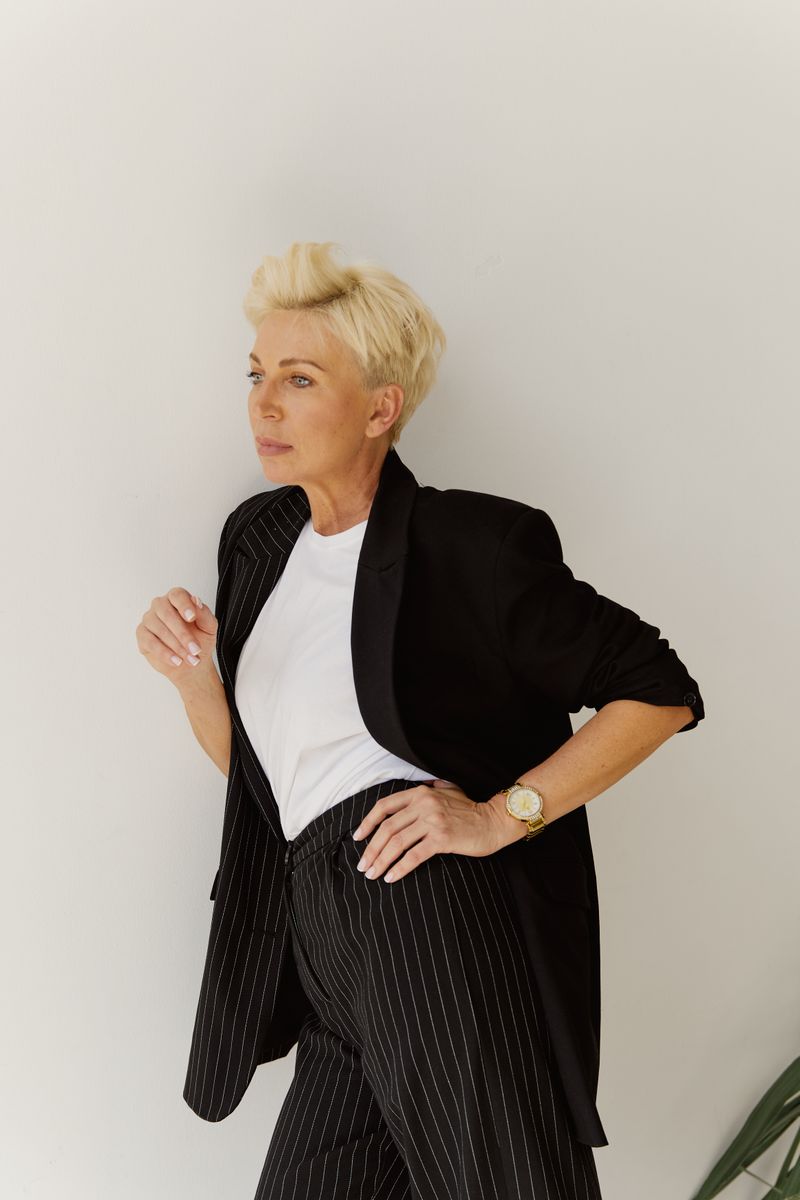 Elegant woman in a black suit against a white wall