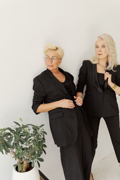 Free Stylish women in black suits striking a pose indoors with a green plant, exuding elegance. Stock Photo