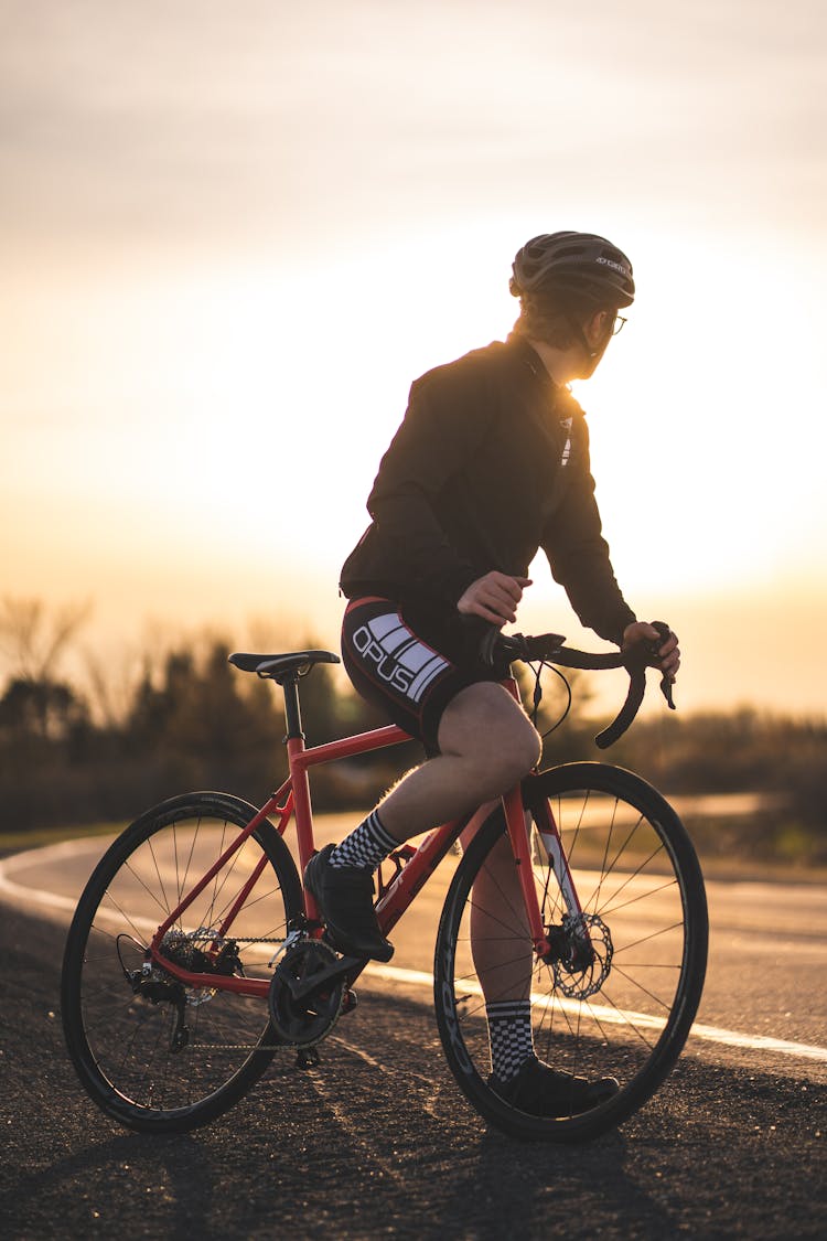 A Man Riding A Red And Black Bicycle