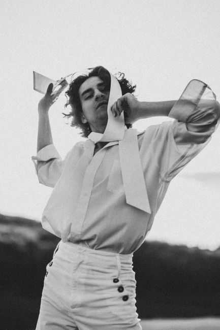 Black and white portrait of a stylish model striking a pose outdoors.