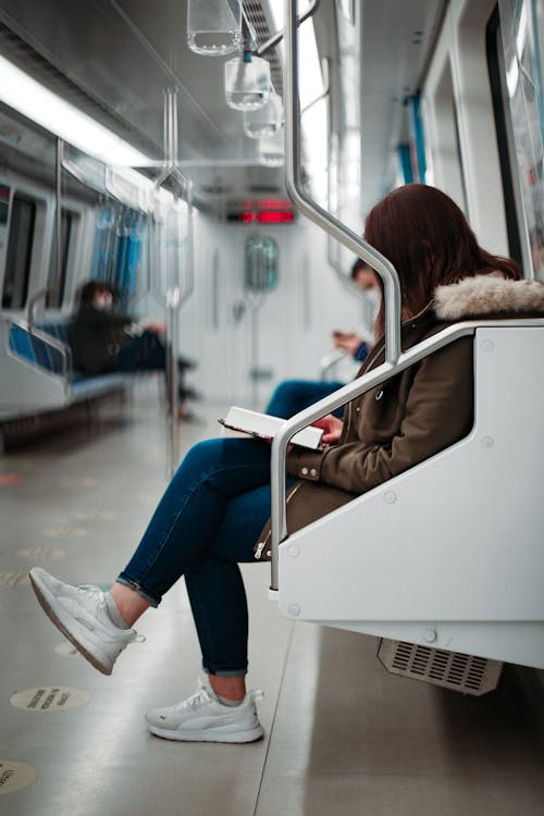 Woman in Brown Jacket Sitting on a Chair in a Train