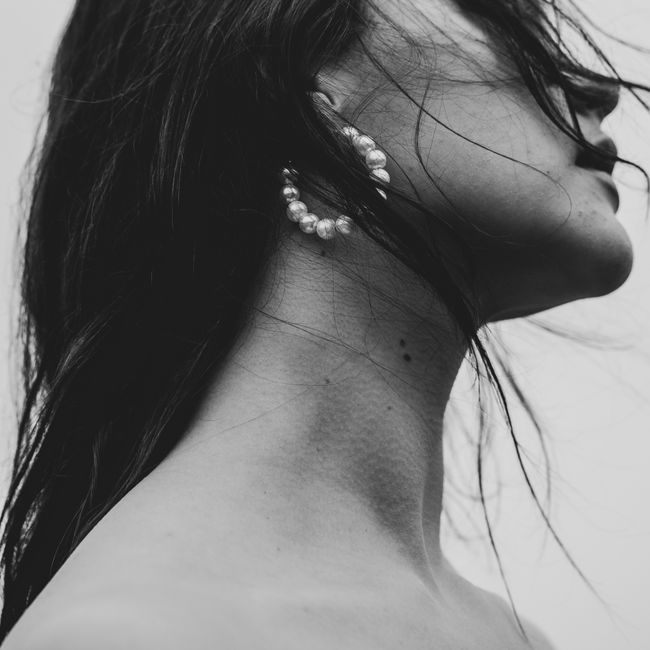 Stylish black and white portrait of woman featuring pearl jewelry and long hair, exuding elegance and grace.