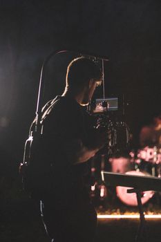 Silhouette of a videographer recording a live concert in a moody setting.