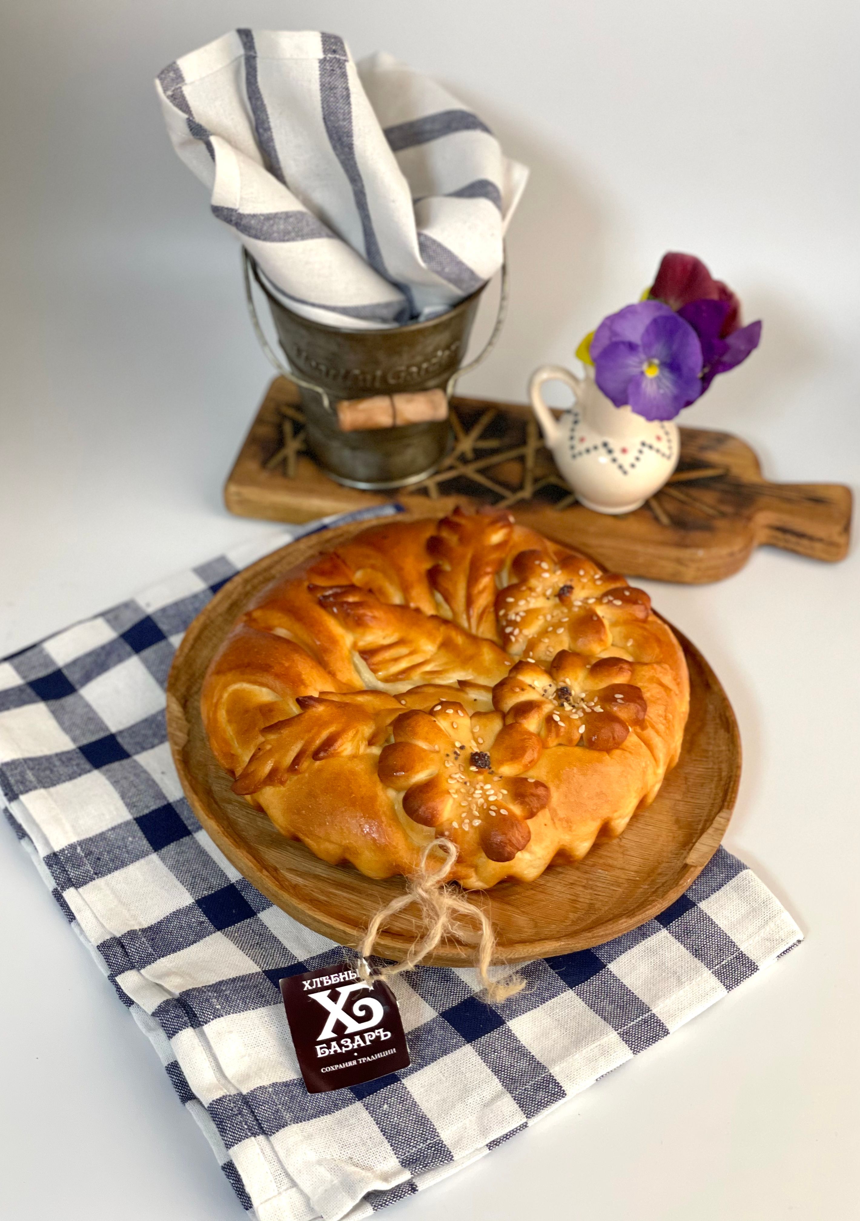 A beautifully baked artisanal bread served on a wooden plate with a colorful table setup.