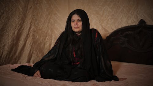 Woman in Black Veil Sitting on a Bed