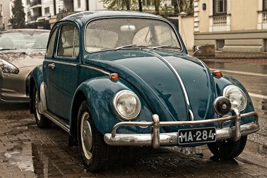 A retro Volkswagen Beetle parked on a rainy city street in Poland, showcasing classic automotive design.