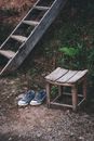 Sneakers near wooden stool and stairs in countryside