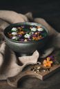 High angle of bowl with flower blossoms and water placed on blanket near cutting board with dried buds and leaves