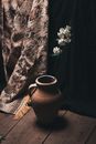 Vase with blossoming branch on floor against curtains